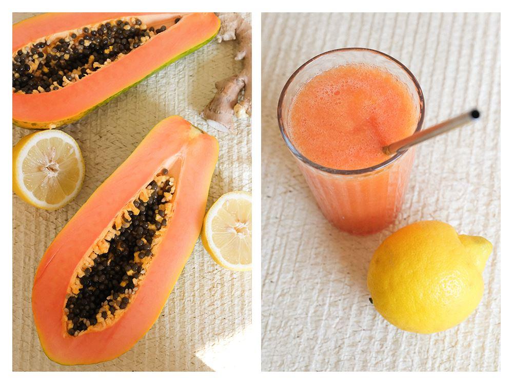 Halbierte Papaya mit Kernen und ein fertiger orangefarbener Smoothie mit Glasstrohhalm
