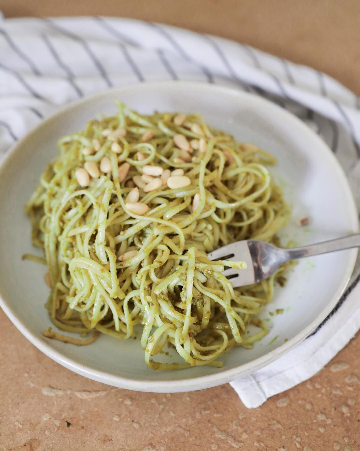 Teller mit Pasta und frischem Spinat-Rucola-Pesto, bestreut mit Pinienkernen