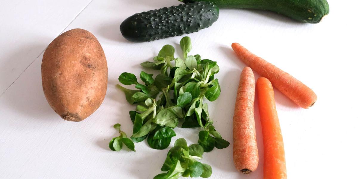 Auswahl an frischem Gemüse wie Karotten, Zucchini, Gurken und Feldsalat für grüne Smoothies.