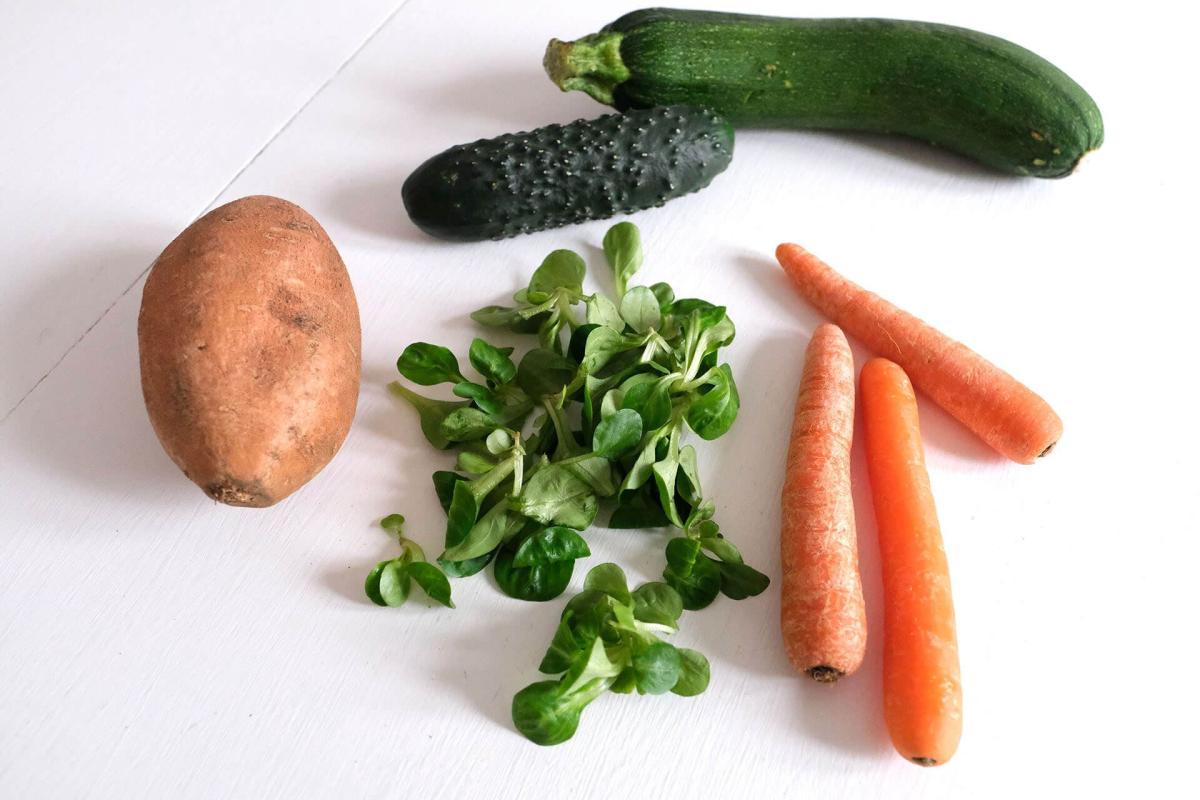 Auswahl an frischem Gemüse wie Karotten, Zucchini, Gurken und Feldsalat für grüne Smoothies.